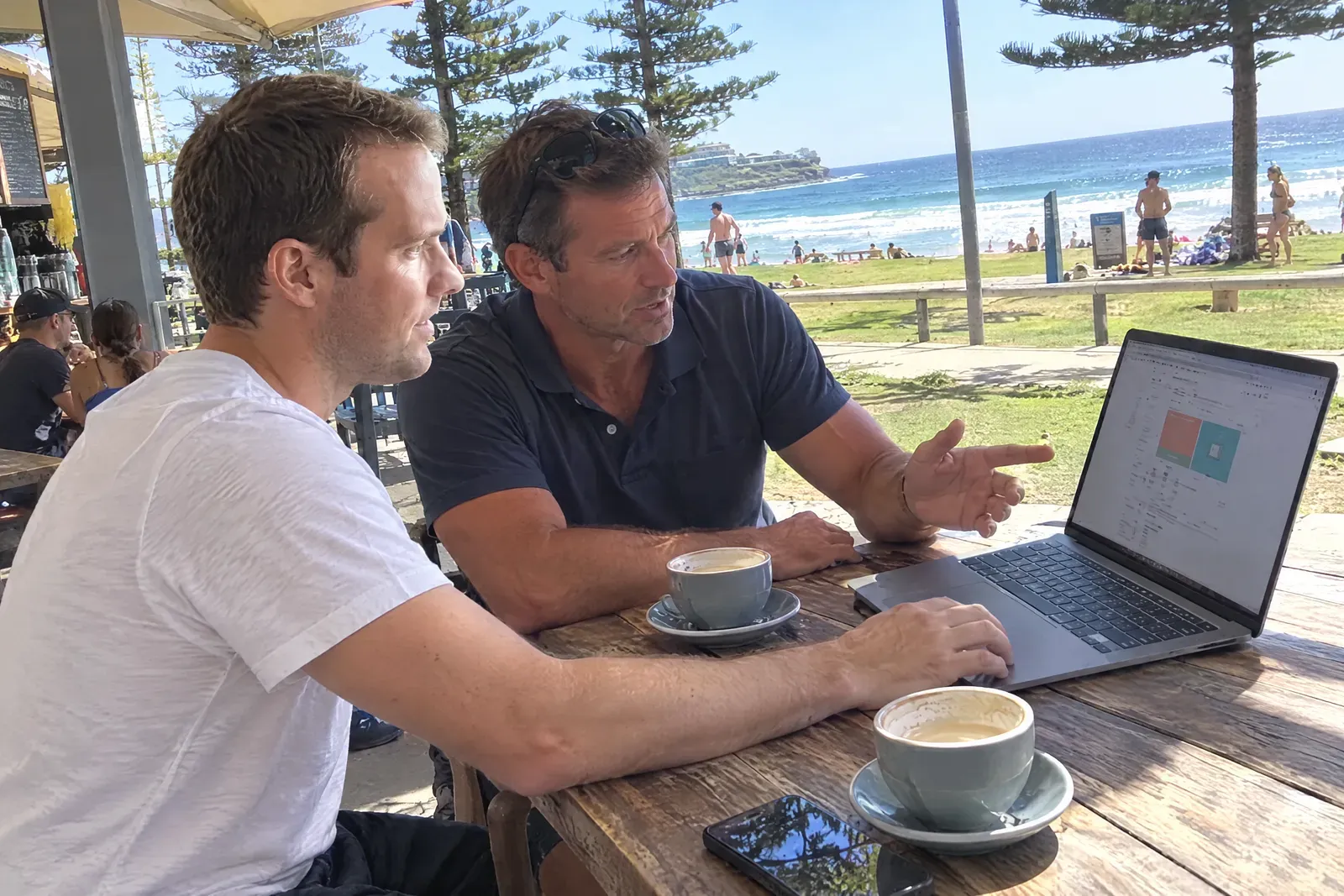 Dru showing a website to a local business owner at a beachside cafe