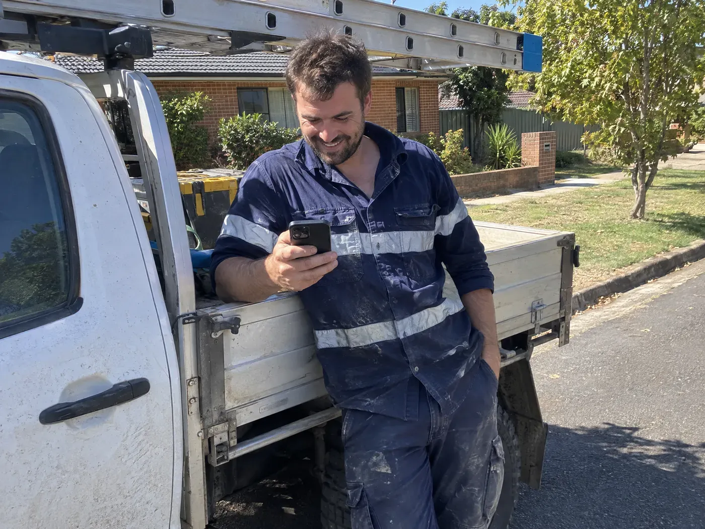 A local electrician smiling as a new enquiry comes through on his phone